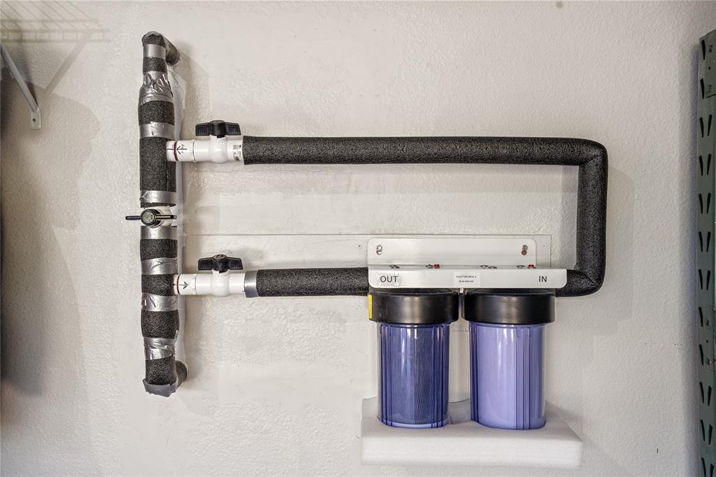 Wall-mounted dual-canister water filtration system with insulated piping and manual shut-off valves