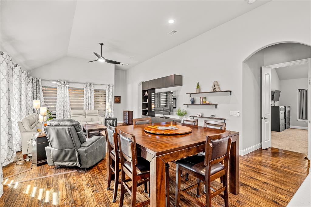 Vaulted ceilings, wood-finish flooring, built-in cabinetry, arched entryway, and wall-mounted shelving