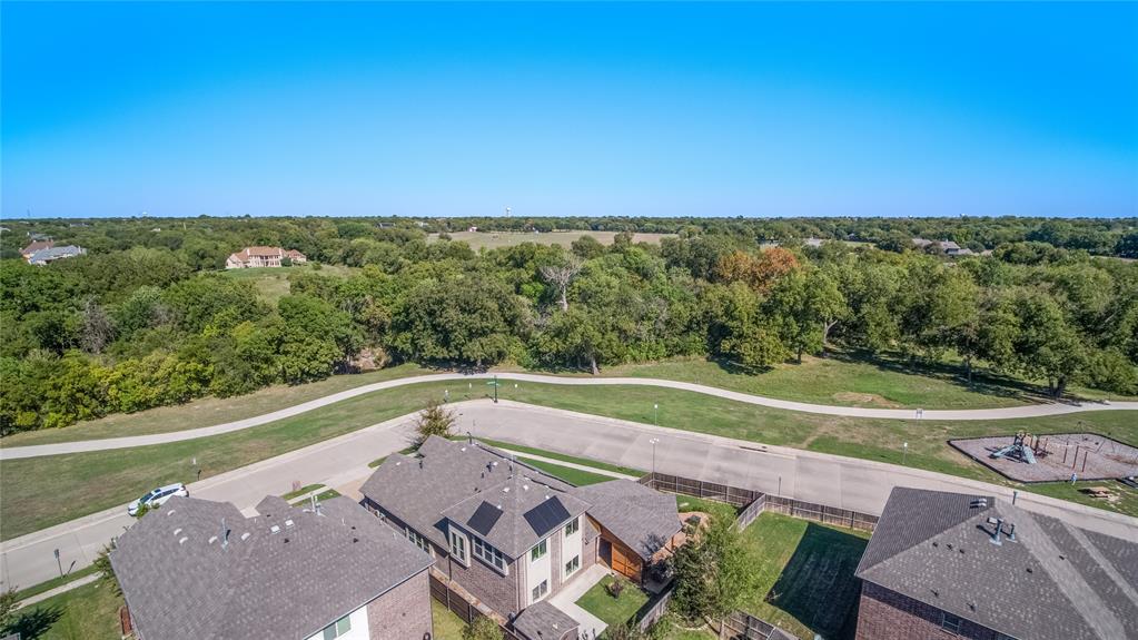 Aerial perspective of a multi-story residence featuring solar panels, a paved sidewalk, and expansive green space