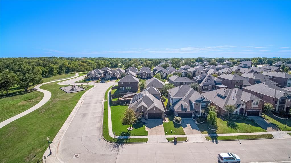 Aerial perspective featuring multi-story residential structures with brick and masonry exteriors, composition shingle roofing, attached garages, and proximity to paved walking paths and green space