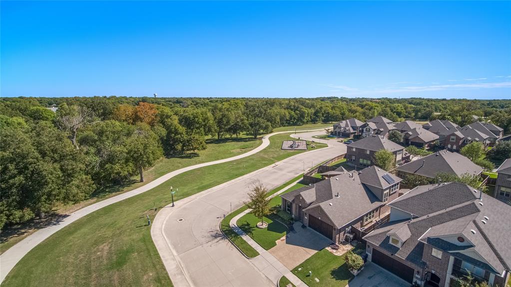 Aerial perspective of neighborhood featuring paved walking trails, expansive green space, mature trees, and multi-story residences