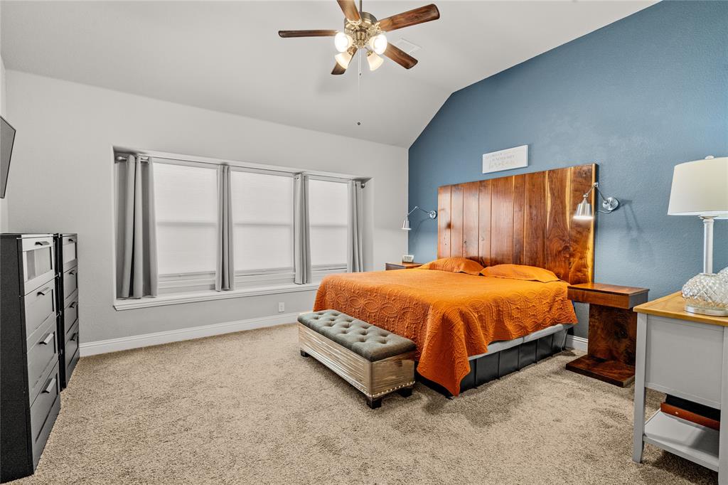 Vaulted ceiling with a wood-finish ceiling fan, expansive triple-pane window configuration, and a built-in vertical wood-plank accent wall with integrated wall-mounted lighting