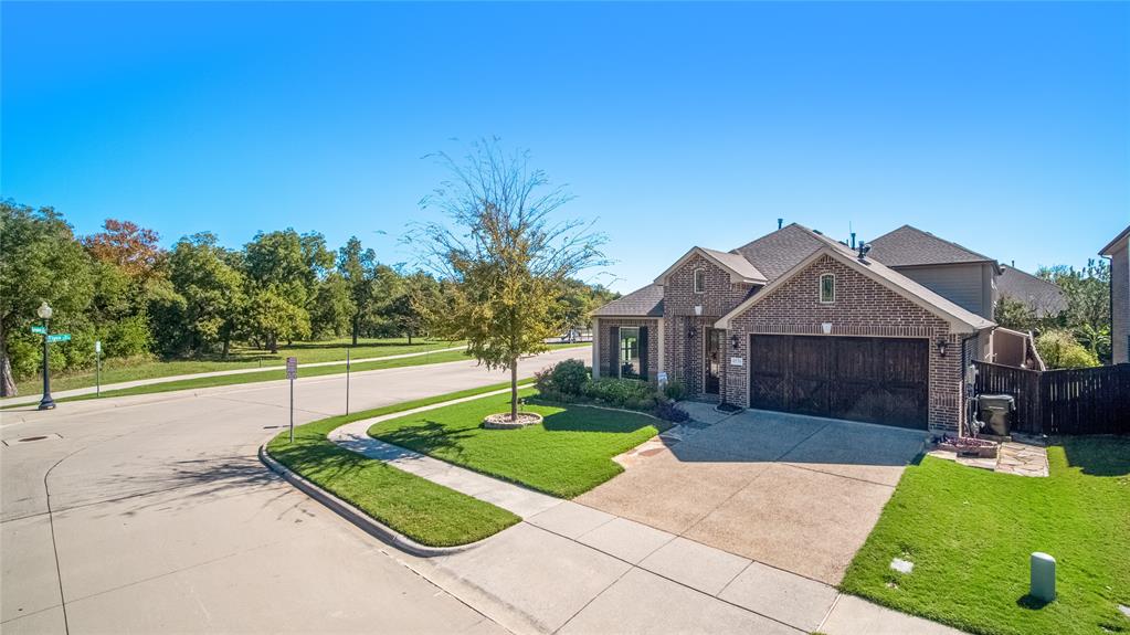 Brick exterior with multi-gabled roofline, concrete driveway, and attached two-car garage