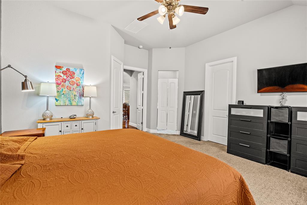Vaulted ceilings, neutral wall palette, ceiling fan with light fixture, carpeted flooring, and multi-panel interior doors