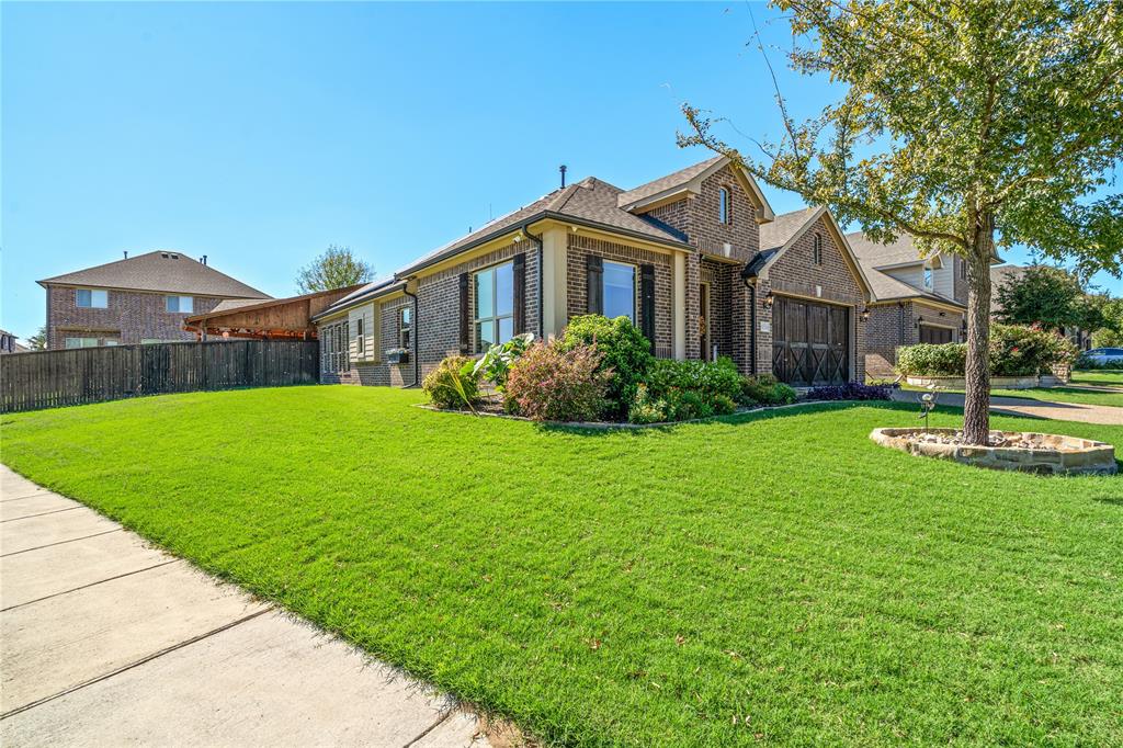 Brick exterior featuring multi-gabled rooflines, dark wood-finish garage doors, decorative shutters, and stone-bordered landscaping