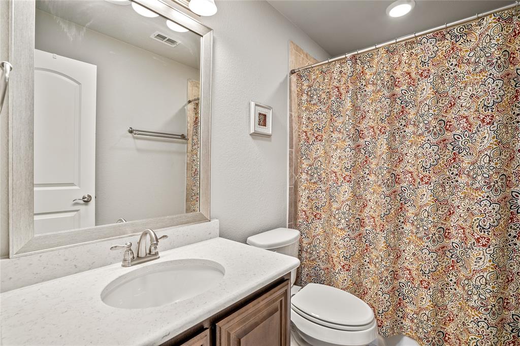Bathroom featuring a vanity with a light-toned countertop, integrated oval basin, framed mirror, polished metal hardware, and a tub-shower combination