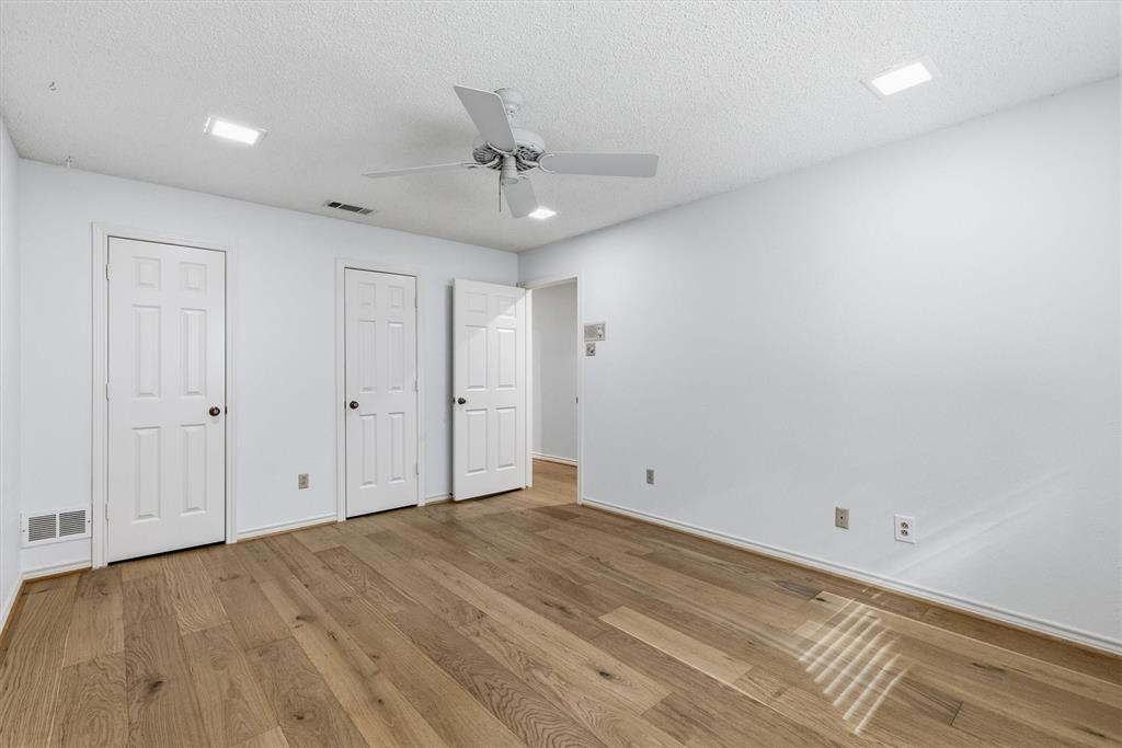 Wood-finish flooring, white paneled interior doors, ceiling fan with integrated lighting, and recessed ceiling lights