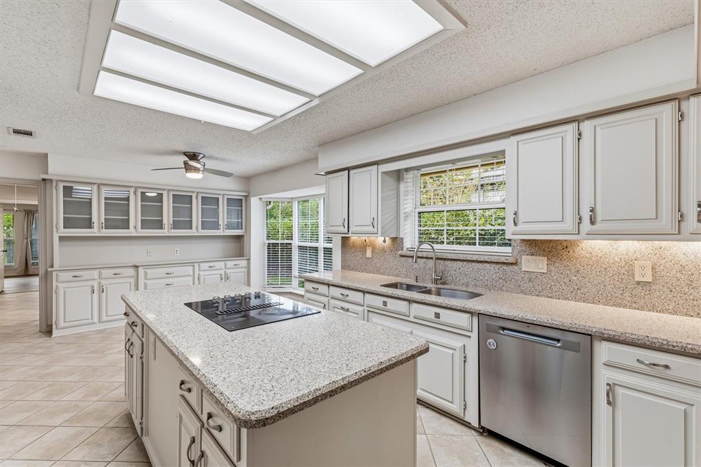 Kitchen featuring painted cabinetry, a central island with a built-in cooktop, stone-finish countertops, stainless steel dishwasher, and recessed ceiling lighting