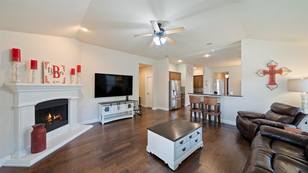 Living area featuring vaulted ceilings, wood-finish flooring, a neutral color palette, and a white mantle fireplace