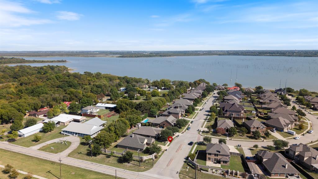 Aerial perspective of residential lots situated along a large body of water, featuring mature trees and paved street infrastructure