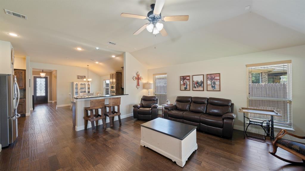 Open concept living area featuring vaulted ceilings, wood-finish flooring, recessed lighting, and a breakfast bar with built-in cabinetry