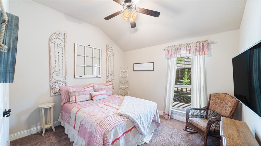 Vaulted ceiling featuring a central multi-blade ceiling fan with integrated light fixture and carpeted flooring