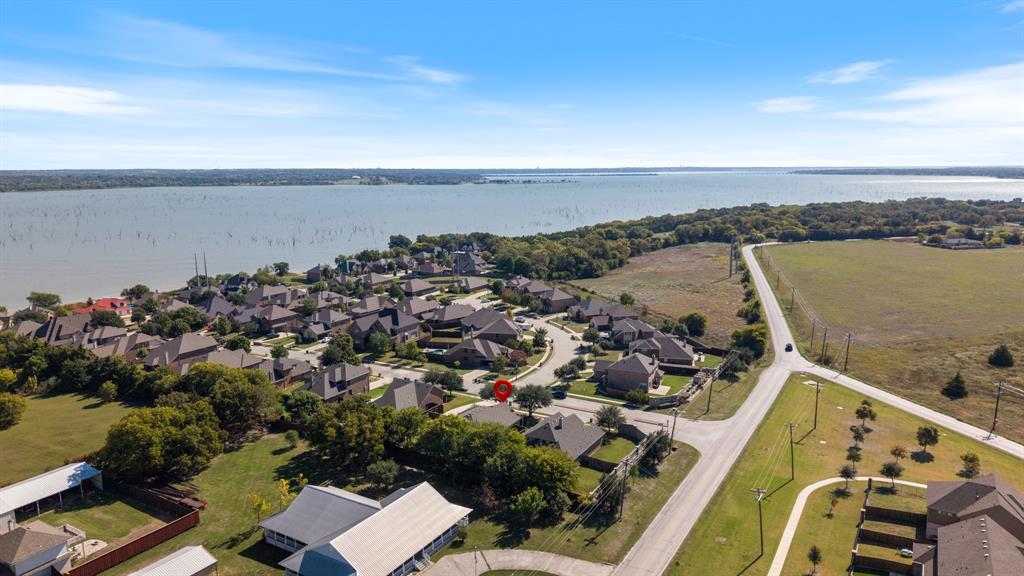 Aerial perspective of residential property situated in a waterfront community featuring mature trees, expansive open land, and proximity to a large reservoir