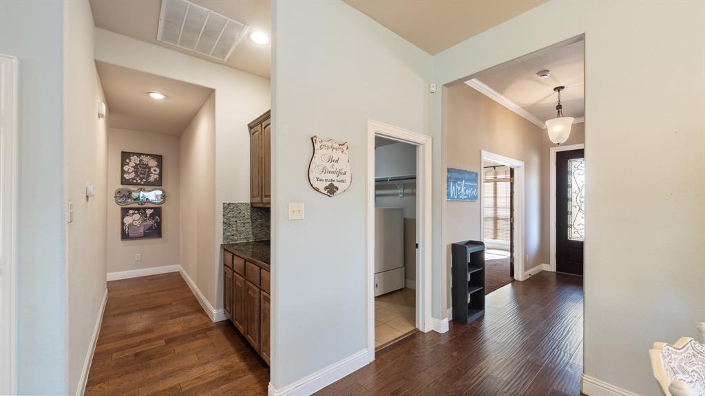Wood-finish flooring, built-in cabinetry with stone-surface countertop, recessed lighting, and a glass-paneled entry door
