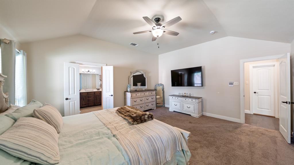 Vaulted ceiling featuring a central multi-blade ceiling fan, wall-to-wall carpeting, and neutral interior wall paint