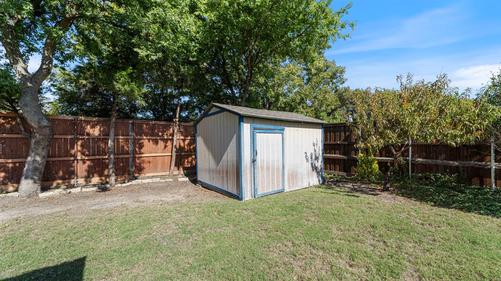 Backyard featuring a wood storage shed, privacy fencing, and mature trees