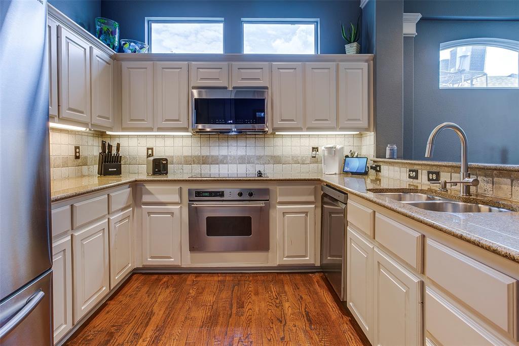 Kitchen featuring wood-finish flooring, light-toned cabinetry, stainless steel appliances, and stone countertops