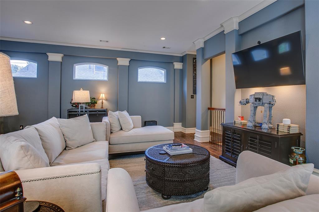 Spacious living area featuring wood-finish flooring, recessed lighting, and decorative architectural columns