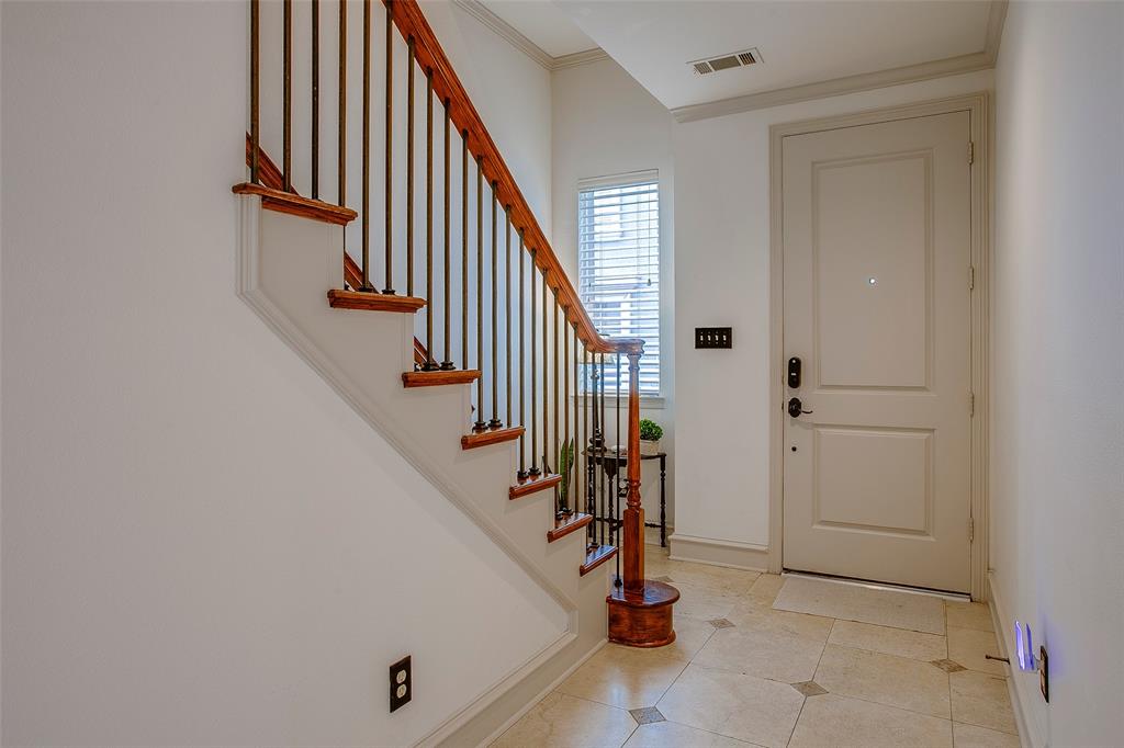 Foyer entrance featuring a paneled door, tiled flooring with accent squares, and a staircase with wood treads and iron balusters