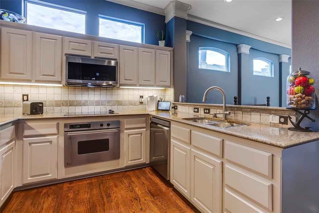 Kitchen featuring light-toned cabinetry, granite countertops, stainless steel appliances, and wood-finish flooring