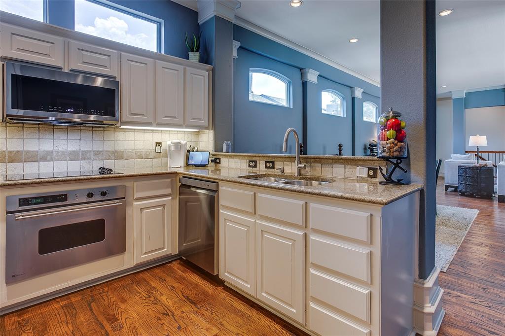Kitchen featuring light-toned cabinetry, stainless steel appliances, a tiled backsplash, and granite countertops