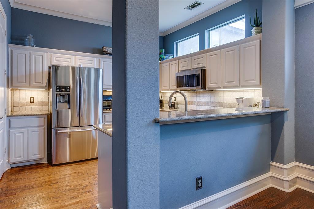 Kitchen featuring white shaker cabinetry, stainless steel appliances, light-toned countertops, and wood-finish flooring