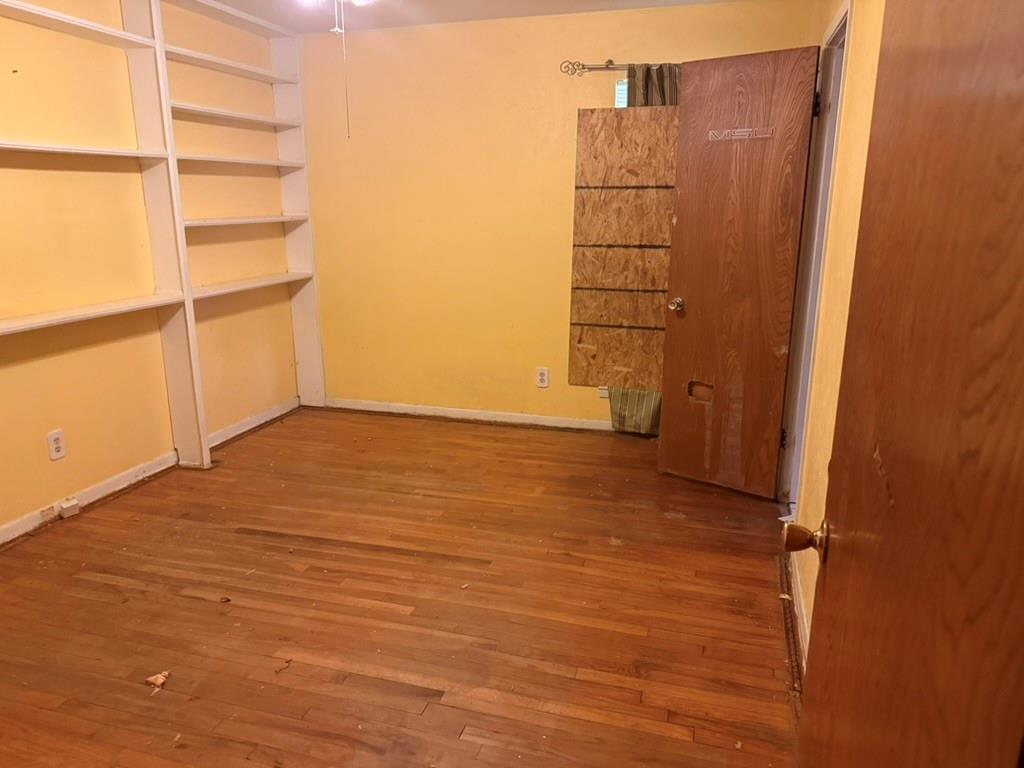 Room featuring wood-finish flooring and floor-to-ceiling built-in white shelving