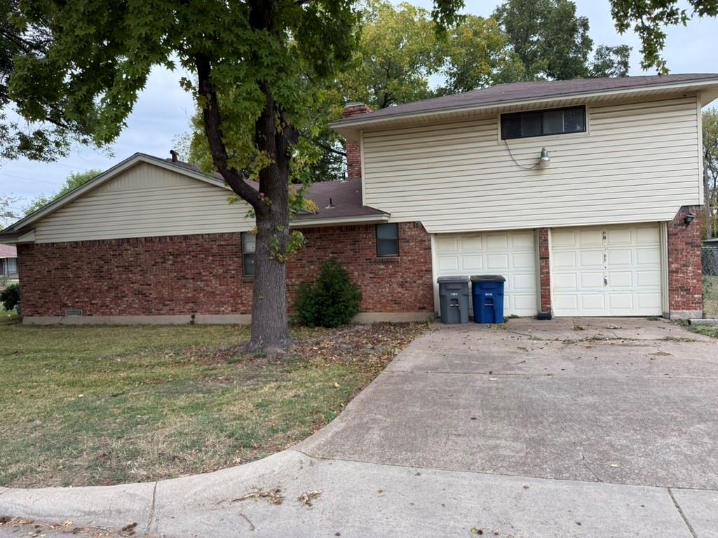 Multi-level exterior featuring a brick and vinyl siding facade, a two-car garage, and an asphalt driveway
