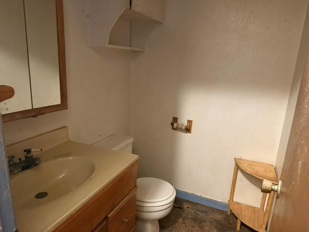 Vanity featuring an integrated sink, wooden cabinetry, wall-mounted medicine cabinet, overhead built-in shelving, and tile flooring