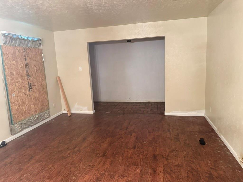 Interior room featuring wood-finish flooring and a large rectangular cased opening leading to a tiled area