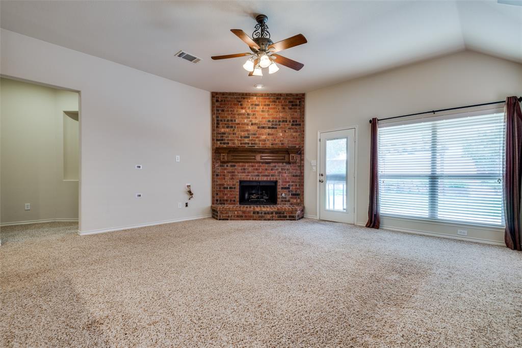 Unfurnished living room featuring visible vents, baseboards, a brick fireplace, a ceiling fan, and carpet floors