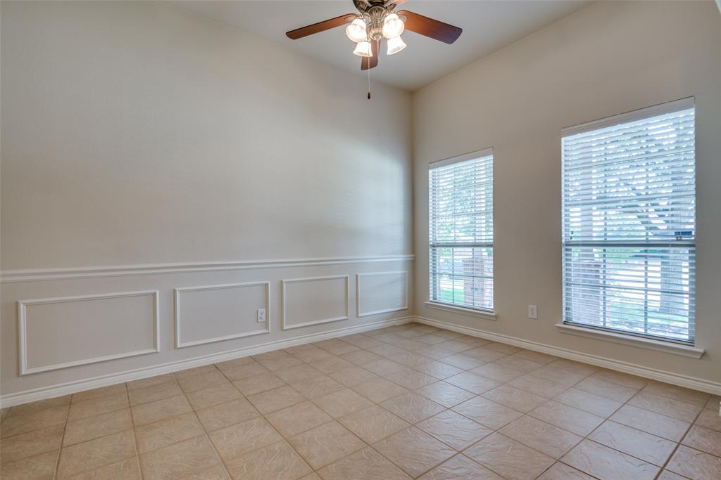 Empty room with a decorative wall, light tile patterned floors, ceiling fan, and a wainscoted wall