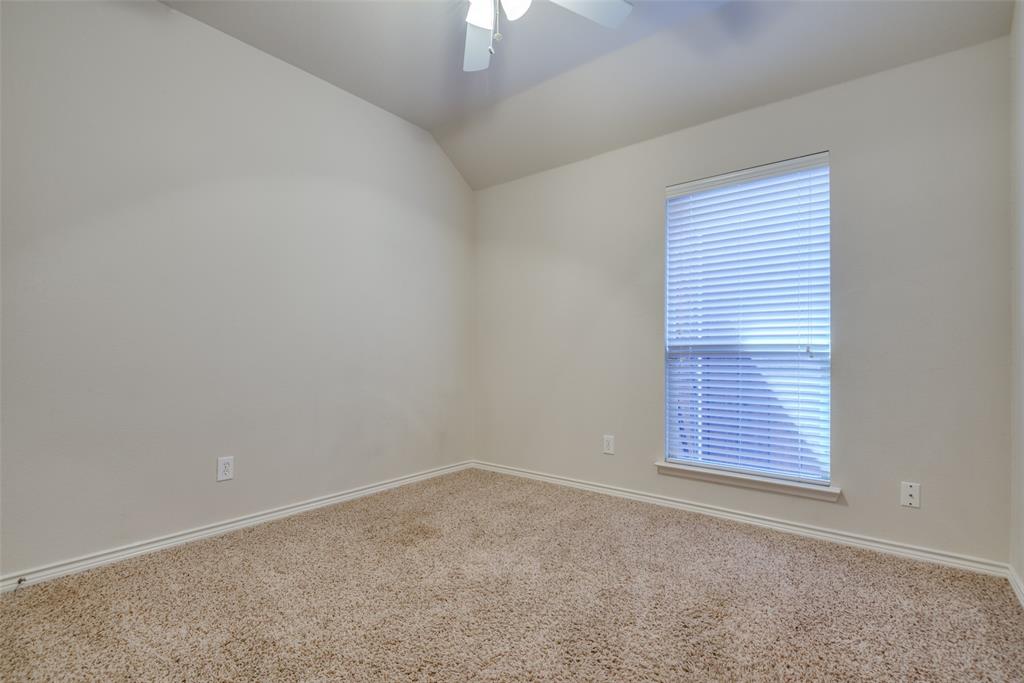 Carpeted empty room with ceiling fan, baseboards, and vaulted ceiling