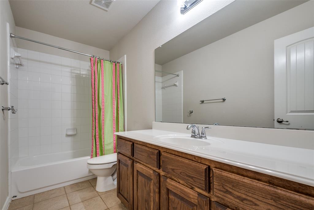Bathroom featuring visible vents, toilet, shower / bathtub combination with curtain, vanity, and tile patterned floors