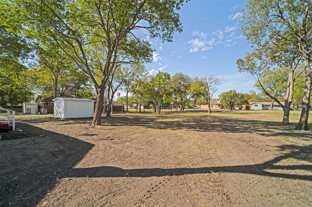 Expansive lot featuring mature trees and a detached storage shed