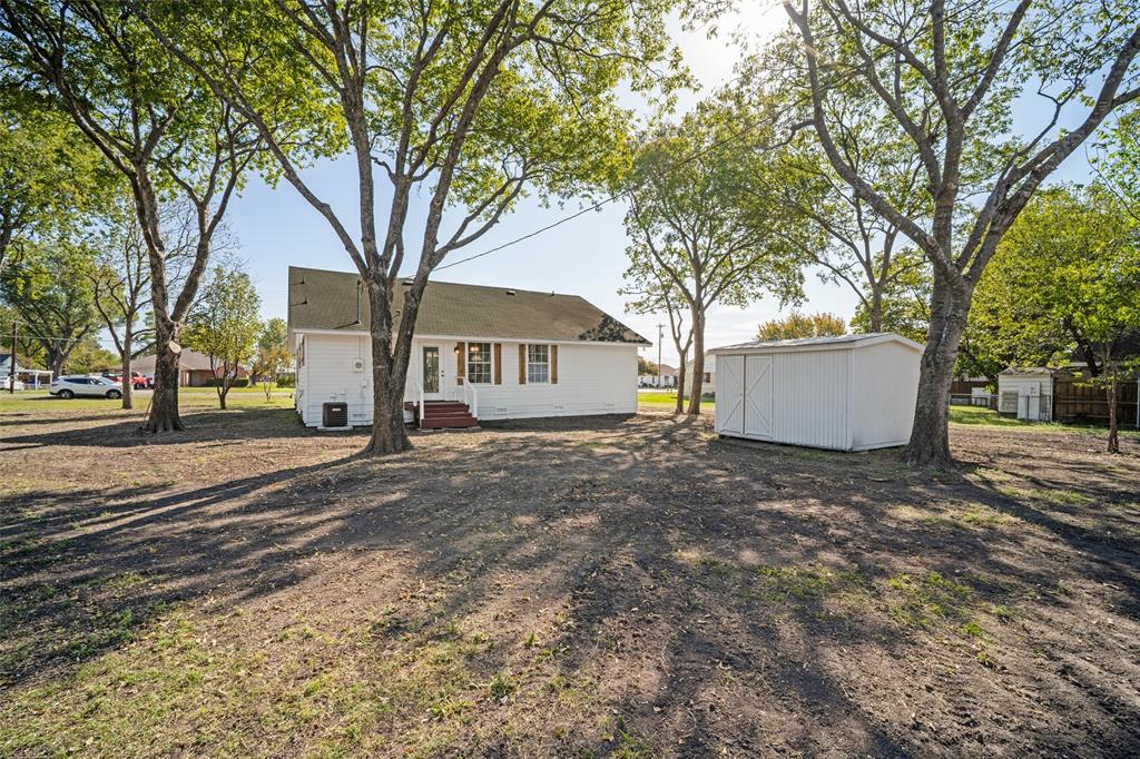Expansive rear grounds featuring mature trees and a detached storage shed