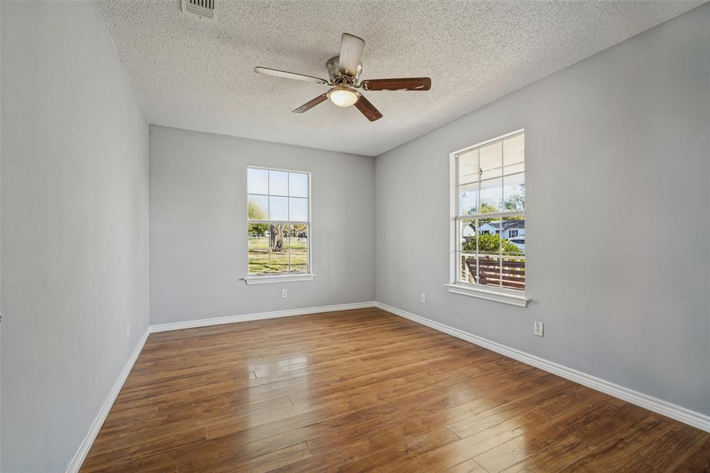 Room featuring wood-finish flooring, dual windows with grid detailing, and a central ceiling fan with integrated lighting Room featuring wood-finish flooring, dual windows with grid detailing, and a central ceiling fan with integrated lighting