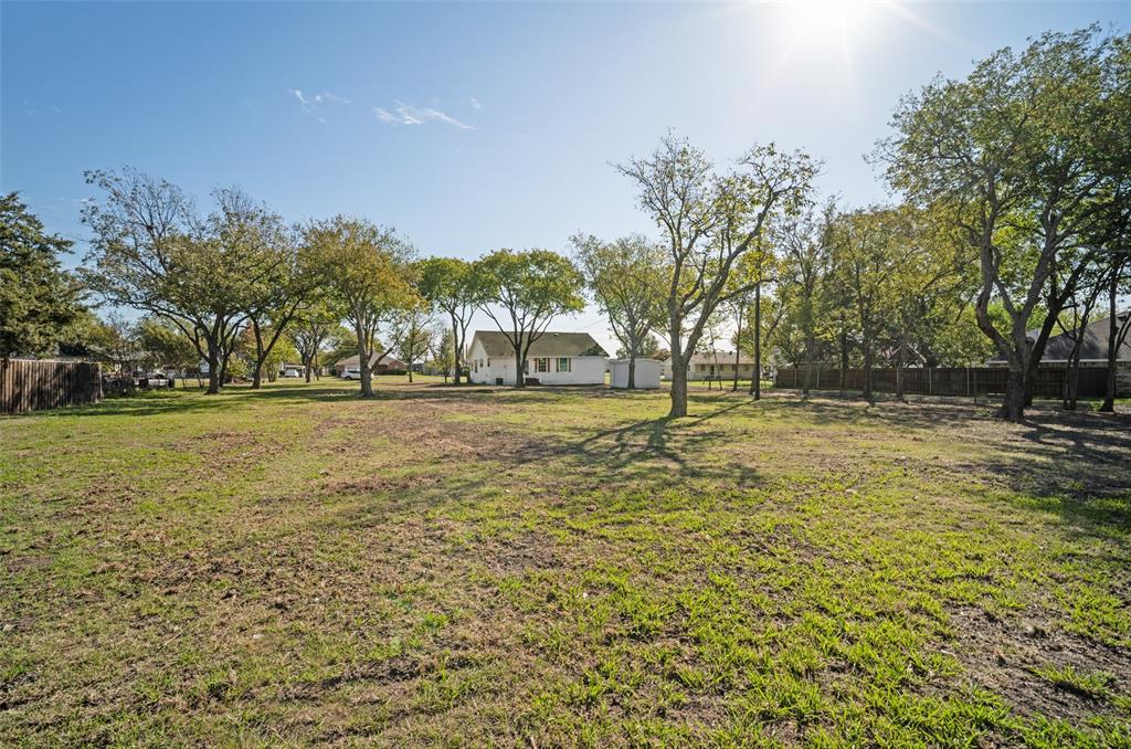 Expansive backyard featuring mature trees, wood privacy fencing, and a detached storage structure