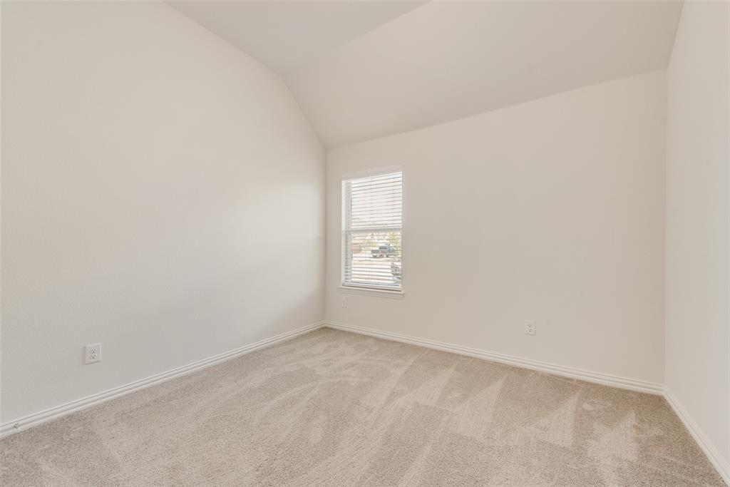 Room featuring neutral wall tones, carpeted flooring, and a vaulted ceiling with an inset window