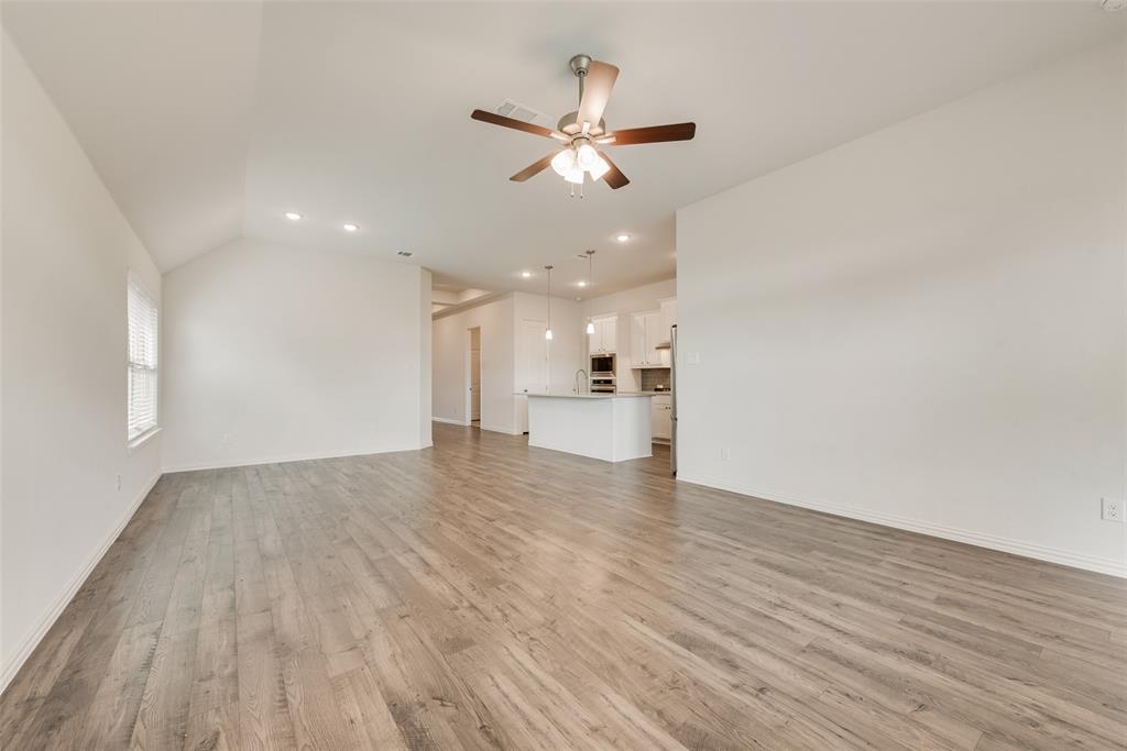 Open-concept interior featuring vaulted ceilings, wood-finish flooring, recessed lighting, and a ceiling fan
