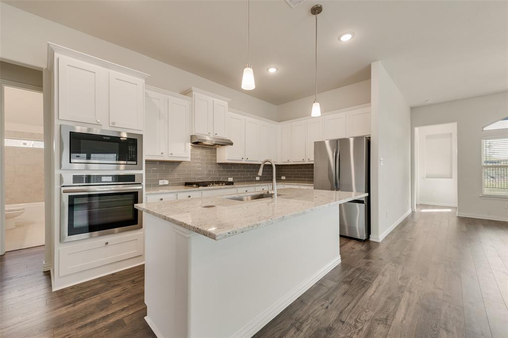 Kitchen featuring white cabinetry, stone countertops, stainless steel wall ovens, a tile backsplash, and wood-finish flooring