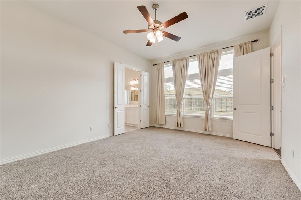 Interior space featuring plush carpeting, a multi-blade ceiling fan with integrated lighting, and expansive windows with transom panels