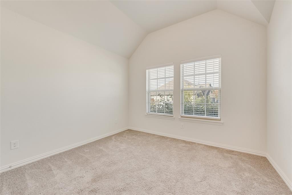Interior space featuring vaulted ceilings, neutral wall tones, plush wall-to-wall carpeting, and double windows with integrated blinds