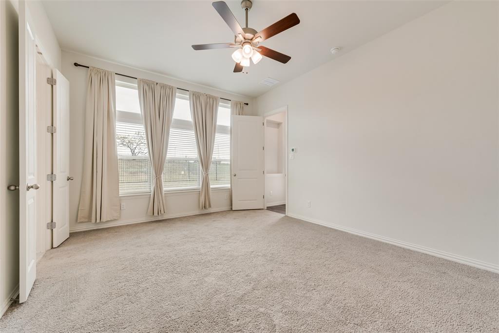 Neutral-toned wall-to-wall carpeting, three-panel oversized windows, and a multi-blade ceiling fan with integrated lighting