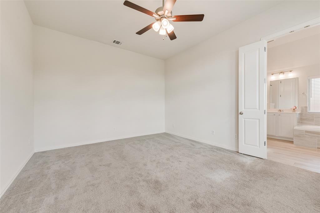 Neutral-toned carpeting, ceiling fan with integrated lighting, and white six-panel door