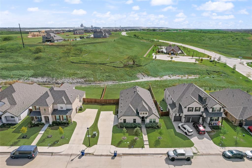 Aerial perspective of residential properties featuring concrete driveways, multi-pitched shingled roofs, masonry facades, and landscaped front lawns