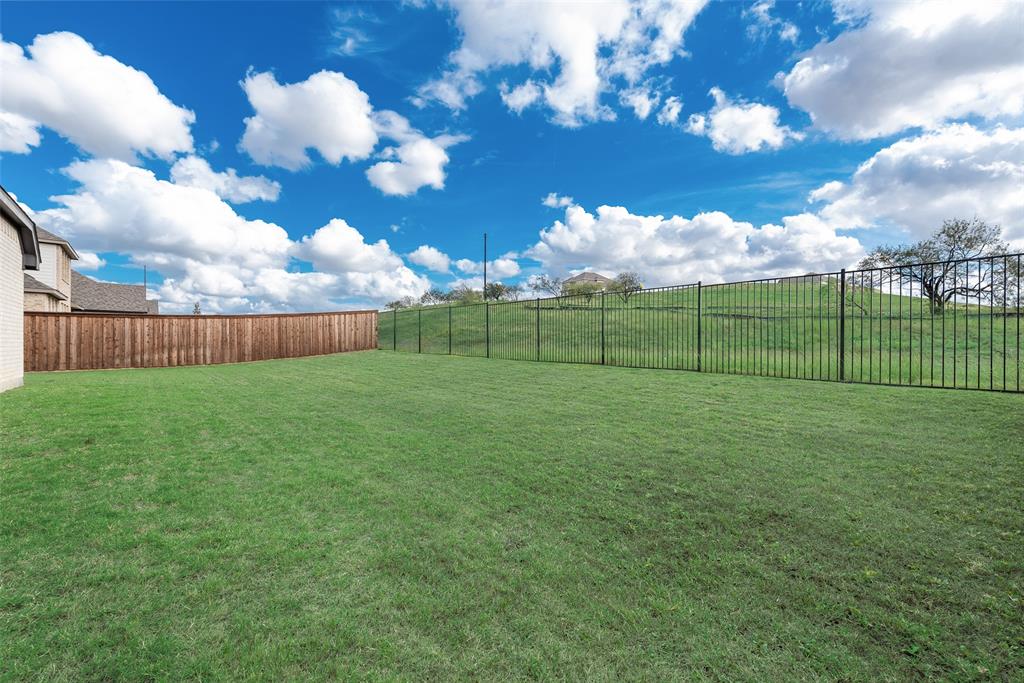 Expansive backyard featuring a level lawn, wood privacy fencing, and metal perimeter fencing