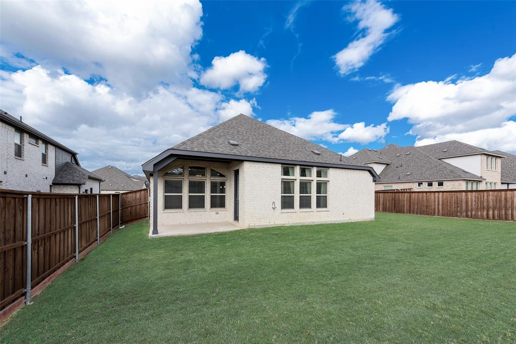 Backyard featuring a covered patio, expansive manicured lawn, and wood privacy fencing