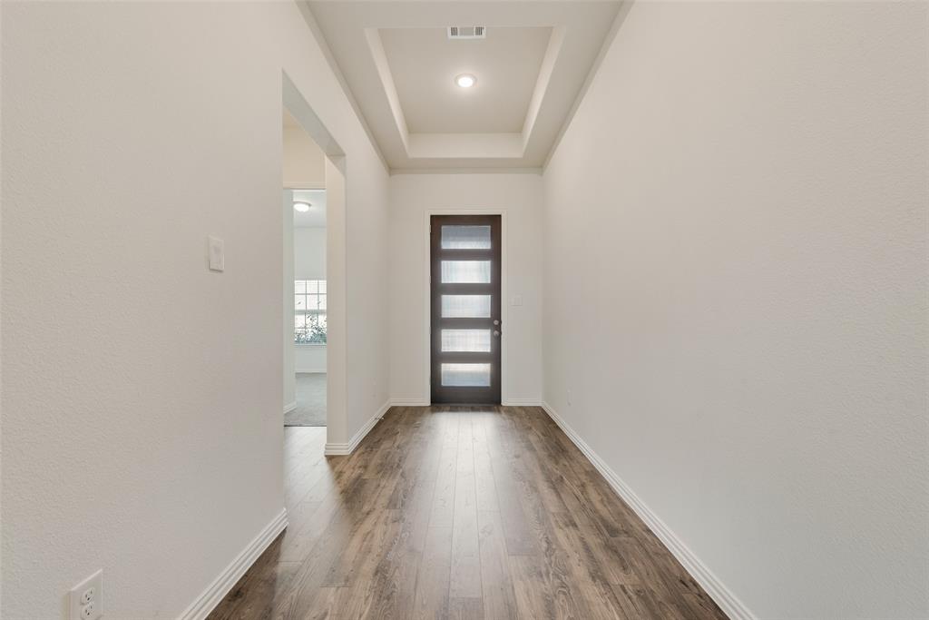 Entryway featuring wood-finish flooring, a tray ceiling, recessed lighting, and a front door with horizontal glass panels