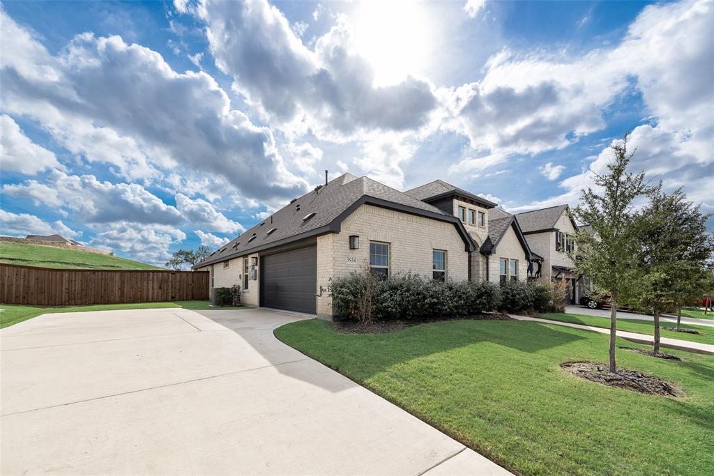 Brick exterior residence featuring a multi-gable roofline, attached multi-car garage, expansive concrete driveway, and professional landscaping